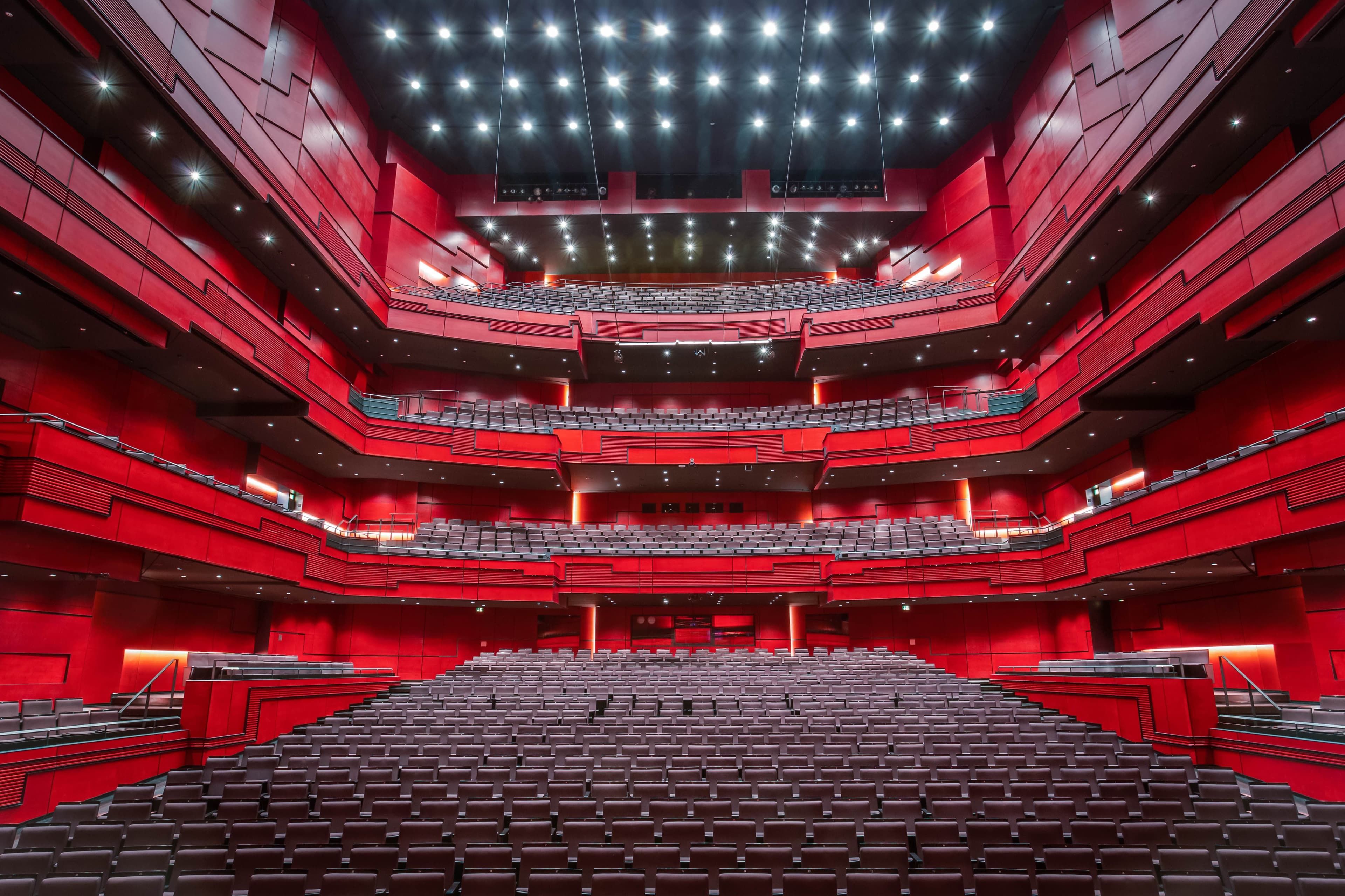 a large empty auditorium with red seats and a stage .